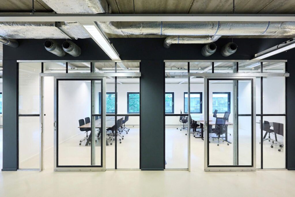 Moderne vergaderruimtes met glazen wanden en industriële plafondafwerking aan het John M. Keynesplein.